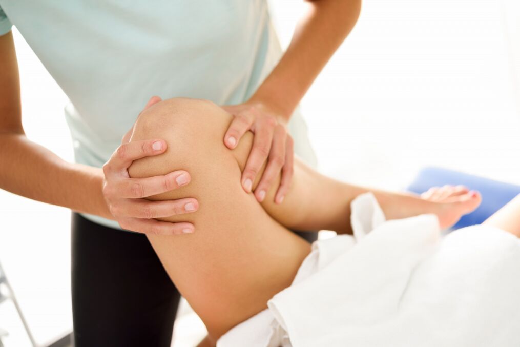Specialist makes therapeutic massage with knee arthritis